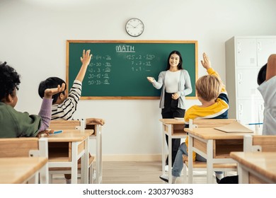 Group of student learn with teacher in classroom at elementary school. Attractive beautiful female instructor master explain and educate young children with happiness and fun activity at kindergarten. - Powered by Shutterstock