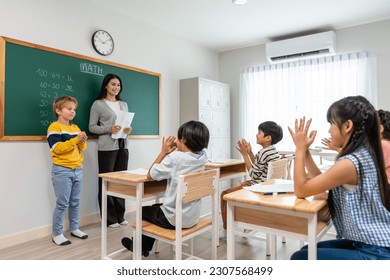 Group of student learn with teacher in classroom at elementary school. Attractive beautiful female instructor master explain and educate young children with happiness and fun activity at kindergarten. - Powered by Shutterstock