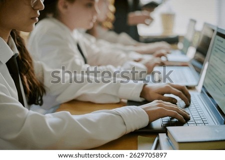 Group of students attentively using laptops in classroom setting, engaging with educational content on screens. Focus on collaborative learning experience among diverse student group