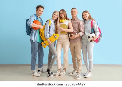 Group of students with backpacks and sport equipment near blue wall - Powered by Shutterstock