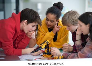 Group of students building and programming electric toys and robots at robotics classroom