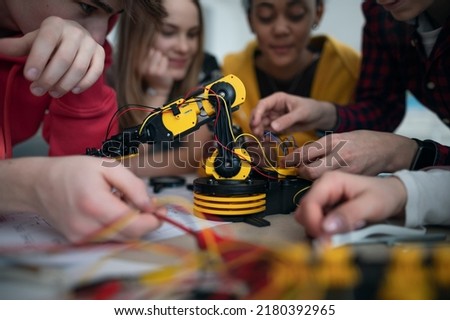 Group of students building and programming electric toys and robots at robotics classroom