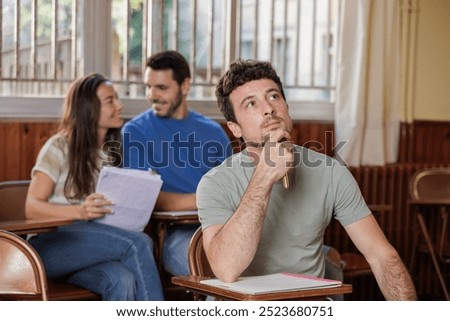 Group of students in class with their notes. Taking an exam, some try to look at the others'. If there are any doubts, they raise their hand and the teacher will help them. Concentration, university.