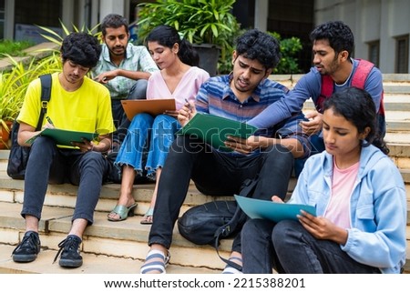 Group of students filling admission application form or preparing for exams on college campus by discussing eachother - concept of graduation, skill development and examination.