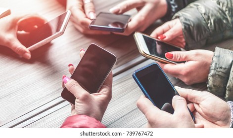 Group of students having fun together with smartphones - Closeup of hands social networking with mobile phone online - Technology and phone addiction concept - Soft focus on left bottom cellphone - Powered by Shutterstock