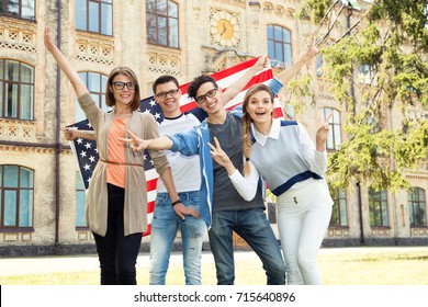 Group of students holding flag of USA on the university campus. Group four happy people having waving American flag. Friends. International language learn course. - Powered by Shutterstock