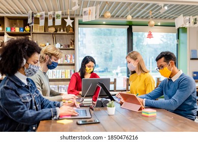 Gruppe von Studenten in der Bibliothek studieren während der Zeit des Koronavirus, Teamarbeit in einem Raum der Zusammenarbeit, soziale Distanzierung und bunt Schutzmasken, neue normale Konzept, virtuelle Verbindung