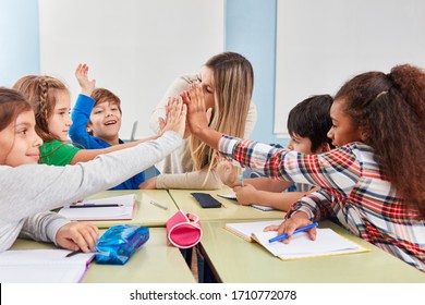 Group of students makes high five in the classroom of a primary school with the teacher