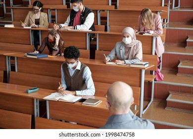 Group of students making notes by desks at lecture - Shutterstock ID 1998474758
