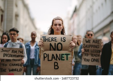 Group Of Students On The Streets Demonstrating Against Climate Change. People Protesting For Problem In Ecology, Environment, Global Warming, Industrial Influence, Climate Emergency.