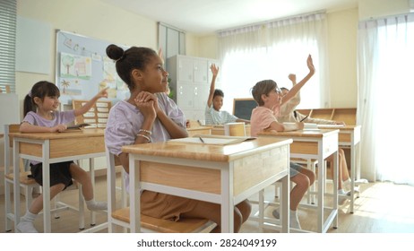 Group of students raising hands eagerly in classroom, representing active participation and engaging learning environment