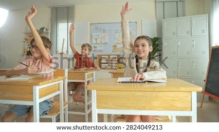Group of students raising hands eagerly in classroom, representing active participation and engaging learning environment