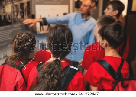 Group of students and school pupils in a science museum exhibition, excursion tour with guide, a docent with a tourist visitors, school field trip, attendees of technical museum exposition gallery