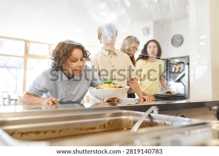 Group of students selecting meals while queuing in a clean and modern school cafeteria.
