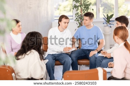 Group of students sitting in circle studying together in study hall of university