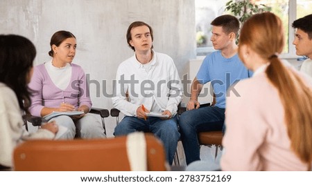 Group of students sitting in circle studying together in study hall of university