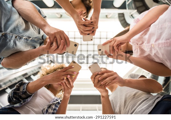 Group of students standing in circle and using phones.