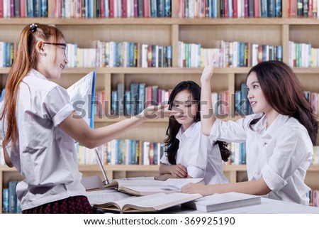 Group of students studying together with one of the students ask a question on her friend