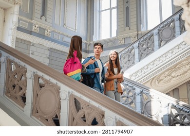 Group of students walking down campus stairs with textbooks and backpacks, classmates after class, education, learning, friendship and student life concept