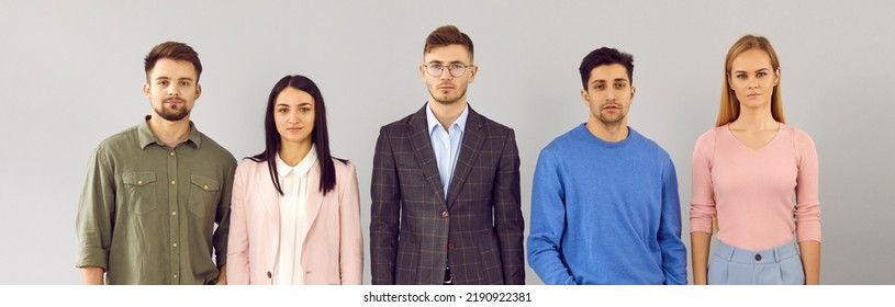 Group Studio Portrait Of Company Staff. Team Of 5 Young Business People In Smart Casual Wear Standing In Row And Looking At Camera With Serious Facial Expressions