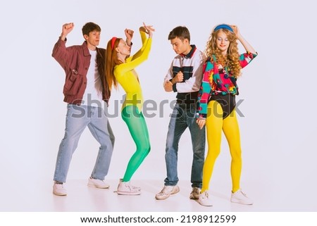 Group of stylish people, boys and girls in bright retro outfits dancing at the disco, party isolated over grey background. Concept of youth, retro style, 90s era, fashion, lifestyle, ad