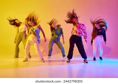 Group of stylish young women dancing contemp, hip hop dance in casual clothes against gradient background in neon light. Concept of youth, street dance, contemporary dance, modern, dynamics - Powered by Shutterstock