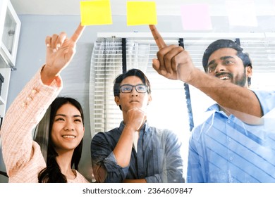 Group of successful Asian businessmen teamwork. Brainstorm meeting with sticky paper notes on the glass wall for new ideas. Using agile methodology for business in a tech start-up office. - Shutterstock ID 2364609847