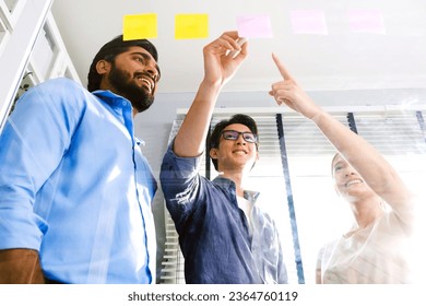 Group of successful Asian businessmen teamwork. Brainstorm meeting with sticky paper notes on the glass wall for new ideas. Using agile methodology for business in a tech start-up office. - Shutterstock ID 2364760119