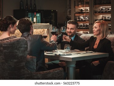 Group Of Successful Business People Clinking Glasses Of Red Wine During Business Dinner In Restaurant