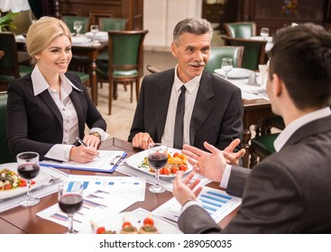 Group of successful business people discussing contract during business lunch.