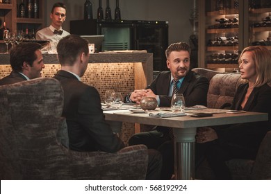 Group of successful business people discussing during business dinner in restaurant.