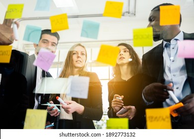 Group Of Successful Business Teamwork. Brainstorm Meeting With Colorful Sticky Paper Note On Glass Wall For New Ideas. Using Agile Methodology And Do Business. Brainstorming In A Tech Start-up Office.