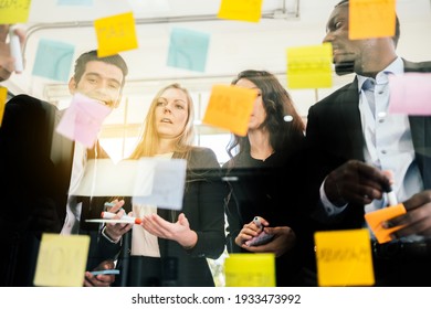 Group of successful business teamwork. Brainstorm meeting with colorful sticky paper note on glass wall for new ideas. Using agile methodology and do business. Brainstorming in a tech start-up office. - Shutterstock ID 1933473992