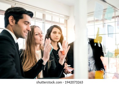 Group of successful business teamwork. Brainstorm meeting with colorful sticky paper note on glass wall for new ideas. Using agile methodology and do business. Brainstorming in a tech start-up office. - Shutterstock ID 1942073263