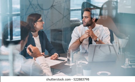 Group of successful businesspeople talking together while working around a table in an office boardroom