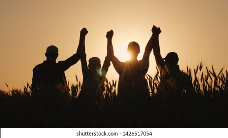 A group of successful young people hold hands, together they raise their upper hand. Successful team and team building concept.