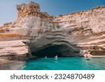 Group of sup boarders enters huge limestone cave on a sea coast