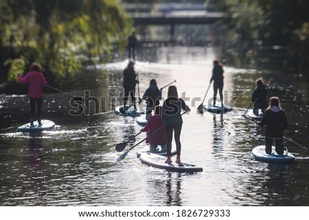 Group of sup surfers stand up paddle board, women stand up paddling together in the city river and canal