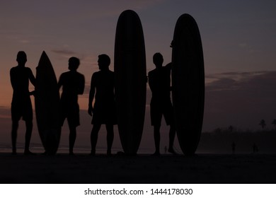 Group Of Surfers In Sillhouette At The Sunset