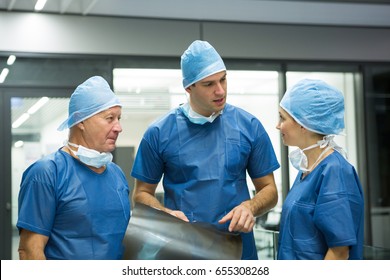 Group of surgeons discussing x-ray in hospital. Healthcare workers in the Coronavirus Covid19 pandemic
