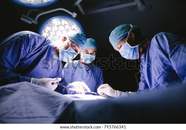 Group of surgeons doing\
surgery in hospital operating theater. Medical team doing critical\
operation.