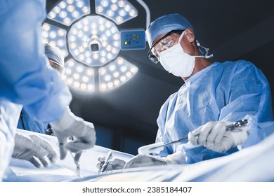 Group of surgeons at operation in operating room at hospital. Surgery, medicine and people concept. Medical case, urgent treatment, microsurgery concept - Powered by Shutterstock