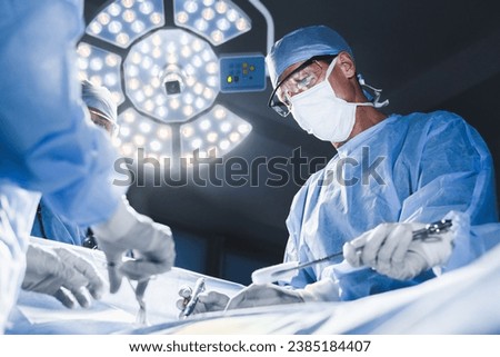 Group of surgeons at operation in operating room at hospital. Surgery, medicine and people concept. Medical case, urgent treatment, microsurgery concept