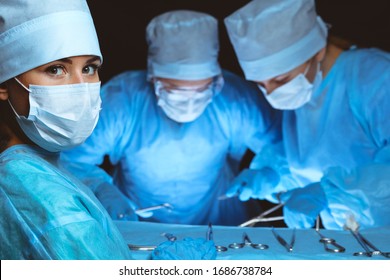 Group of surgeons wearing safety masks performing operation. Medicine concept