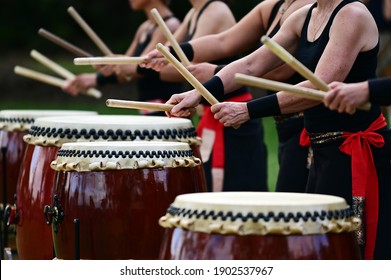 Group of Taiko drummers drumming on Japanese Drums together.