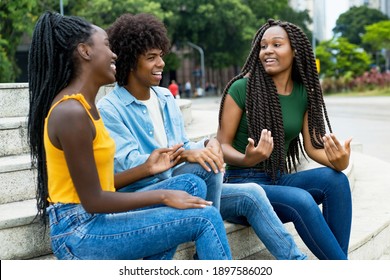 Group of talking african american male and female young adults outdoor in city in summer
