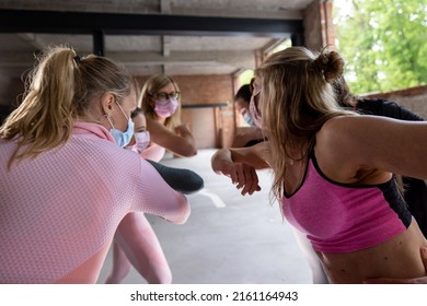 Group Or Team Of Happy Young Sportive Women In A Gym All Cheering With Elbows And Applauding, All Wearing Facemasks To Protect For Coronavirus Or Covid. High Quality FullHD Footage