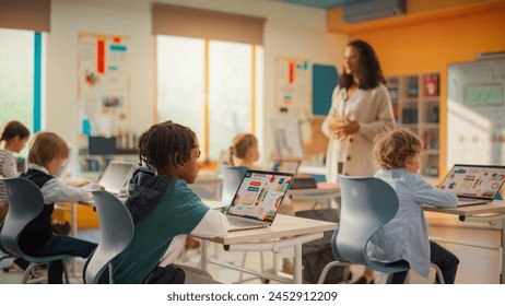 Group of Tech-Savvy Primary School Children Working on Their Laptop and Tablet Computers in Class. Young Female Teacher Educating Kids on Internet Safety, Basic Programming Languages and Formulas