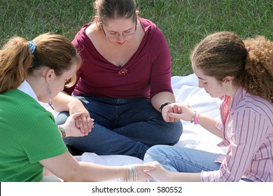 A Group Of Teen Girls Having A Prayer Circle Outdoors.