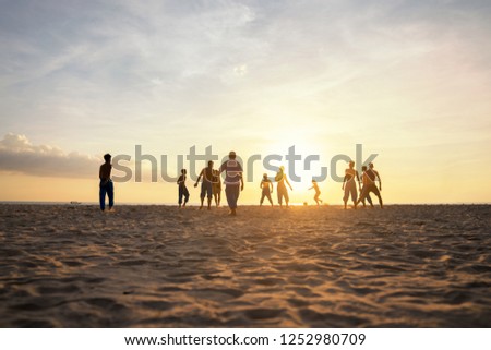Group of teen playing sand football on the beach sunset time
